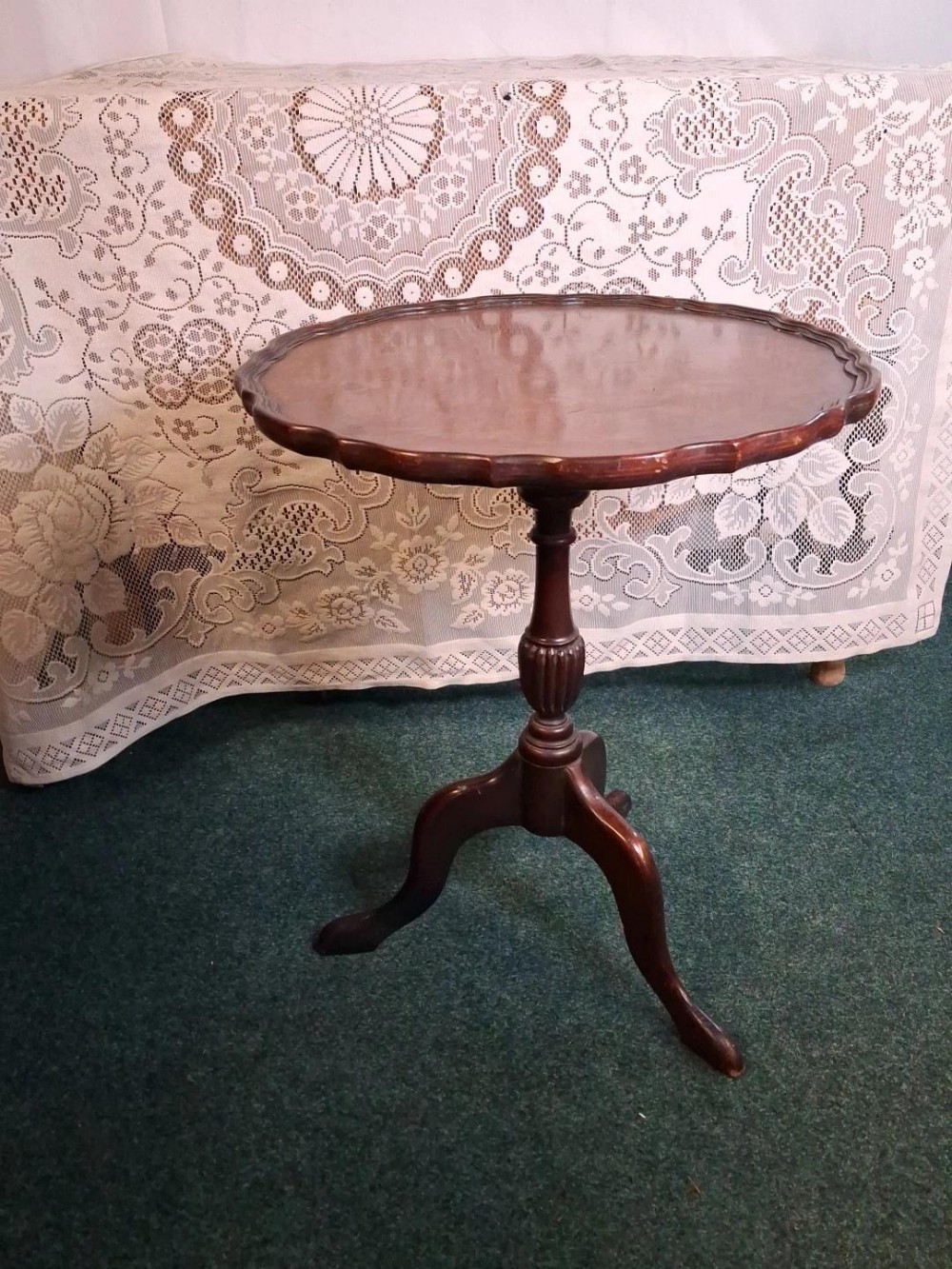 An antique dark mahogany tripod wine table featuring a scalloped piecrust top, turned pedestal stem, and three cabriole legs.
