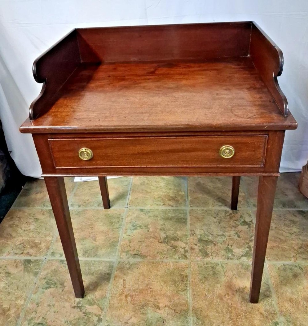 A 19th-century mahogany washstand featuring a raised gallery back, a single drawer with two brass ring handles, and square tapered legs.