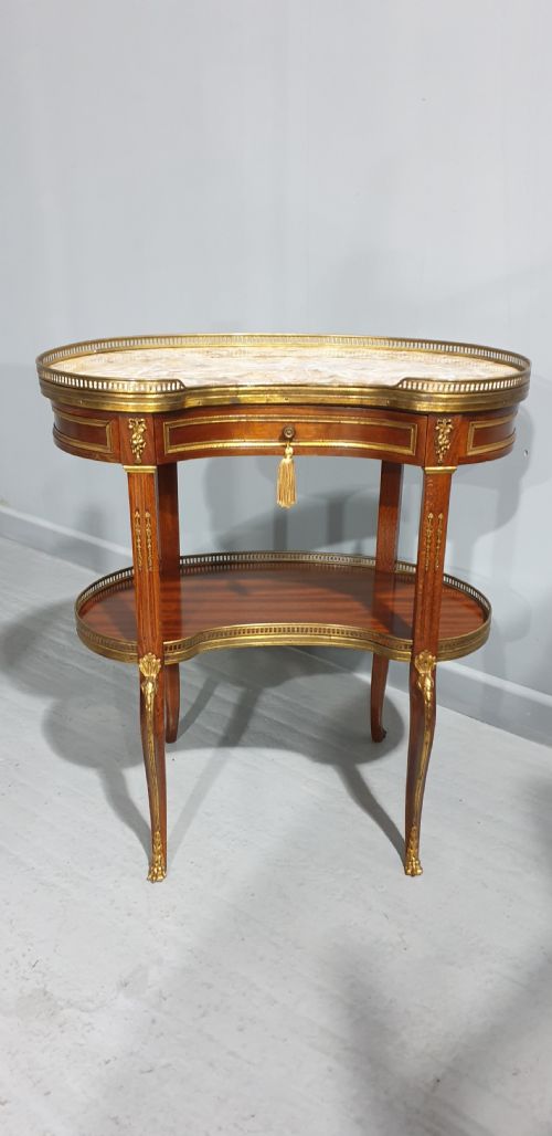 fig 1. A French kidney-shaped mahogany side table featuring a marble top, upper brass gallery, lower shelf, and gilt bronze mounts.