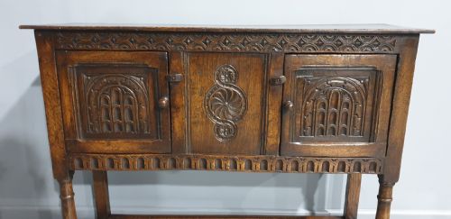 fig 1. A small dark oak carved sideboard with two decorative panelled doors, turned legs, and lower stretchers.