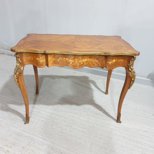 fig 1. A French Louis XV style bureau plat decorated with floral marquetry inlay, curved cabriole legs, and ornate gilt bronze mounts.