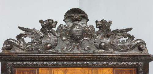 fig 1. A heavily carved dark walnut Italian hall bench featuring a high backrest with intricate pictorial wood marquetry, winged griffin cresting, and lion paw feet.