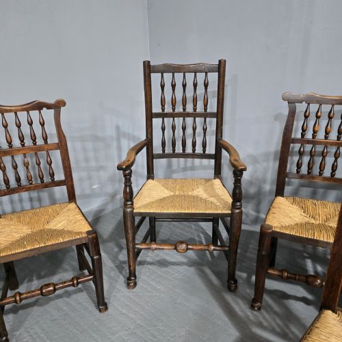 fig 1. A set of six dark brown 19th-century country dining chairs featuring spindle backrests and woven rush seats.