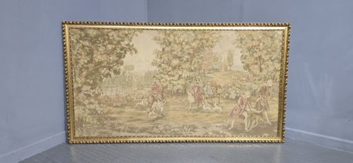 fig 1. A large horizontal framed tapestry depicting an 18th-century style French hunting scene with horse riders, hounds, and a woodland landscape within a gilded beaded frame.