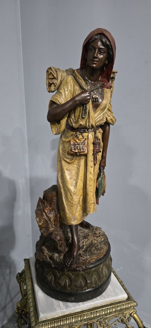 fig 1. A polychrome terracotta sculpture depicting a standing woman dressed as a fisher girl carrying a basket on her back and holding fish.