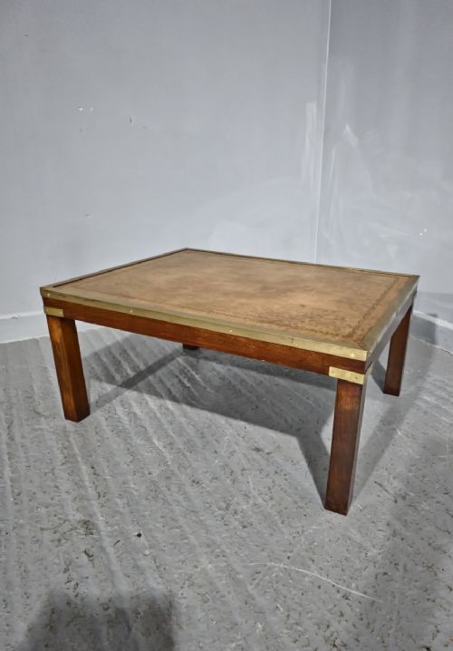 fig 1. A low rectangular mahogany coffee table featuring a leather inset top bordered by brass strapping and brass corner brackets.