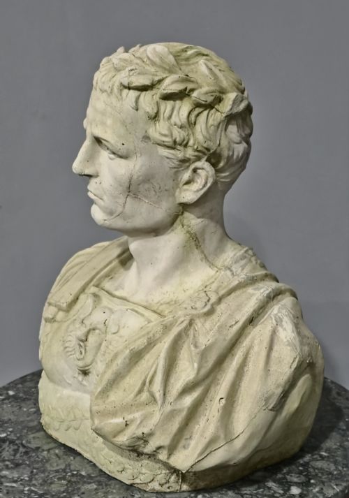 fig 1. A large off-white stone bust depicting Roman General Julius Caesar wearing a laurel wreath and decorated breastplate.