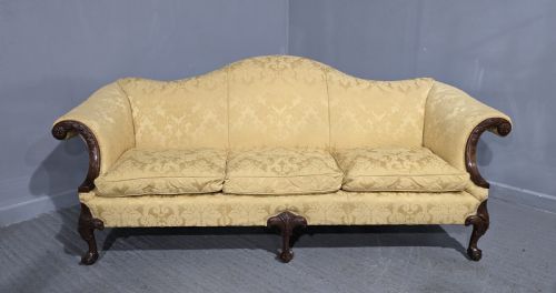 fig 1. A camelback sofa upholstered in patterned yellow damask fabric with carved mahogany scroll arms and cabriole legs terminating in ball and claw feet.