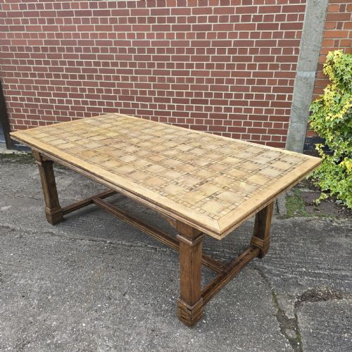fig 1. A large rectangular French refectory dining table featuring a patterned parquet timber top, square block legs, and a low stretcher base.