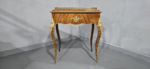 fig 1. A Louis XV style satinwood jardiniere table featuring quartered wood veneer, ornate gilded bronze mounts, cabriole legs, a pierced brass gallery, and a metal liner.