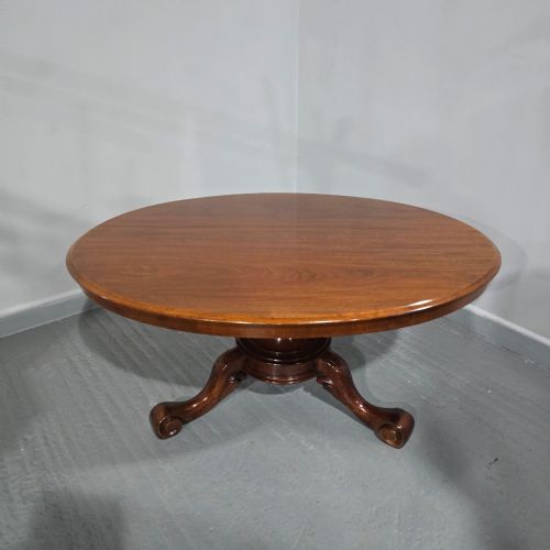 fig 1. An oval mahogany coffee table featuring a polished surface, a central turned pedestal, and four carved cabriole legs terminating in scroll feet.