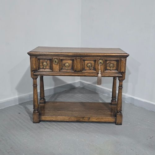 fig 1. A dark oak dresser base featuring two geometric panelled drawers with brass handles, turned front legs, and a bottom shelf.