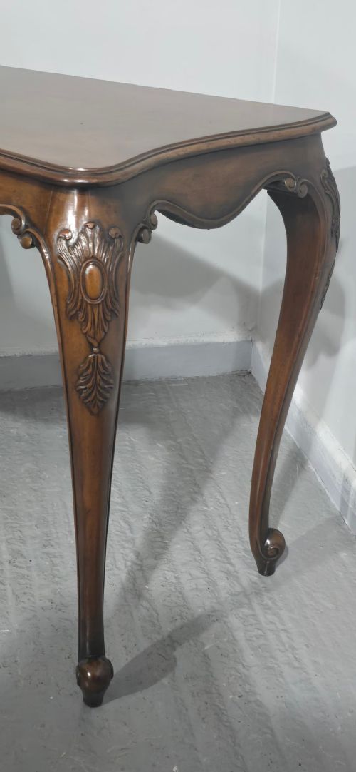 A dark mahogany console table featuring a shaped serpentine top, a central shell carving on the apron, and four cabriole legs. View VII