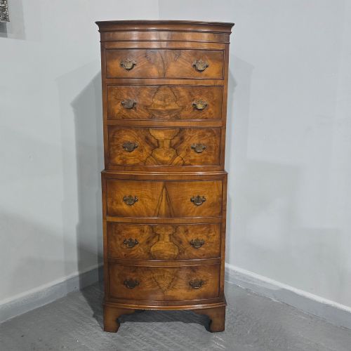 fig 1. A small bowfront burr walnut chest on chest featuring stacked drawers with brass handles and bracket feet.