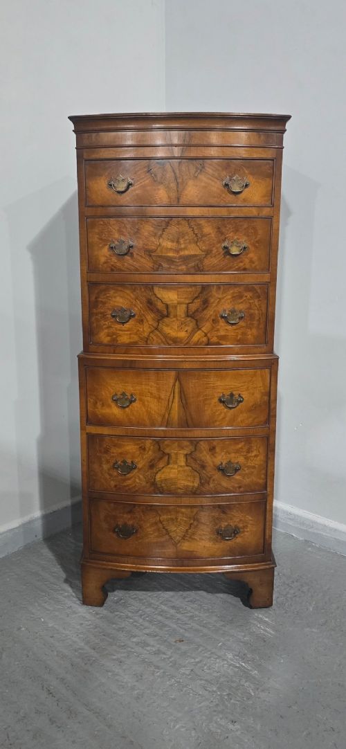 A small bowfront burr walnut chest on chest featuring stacked drawers with brass handles and bracket feet. View III