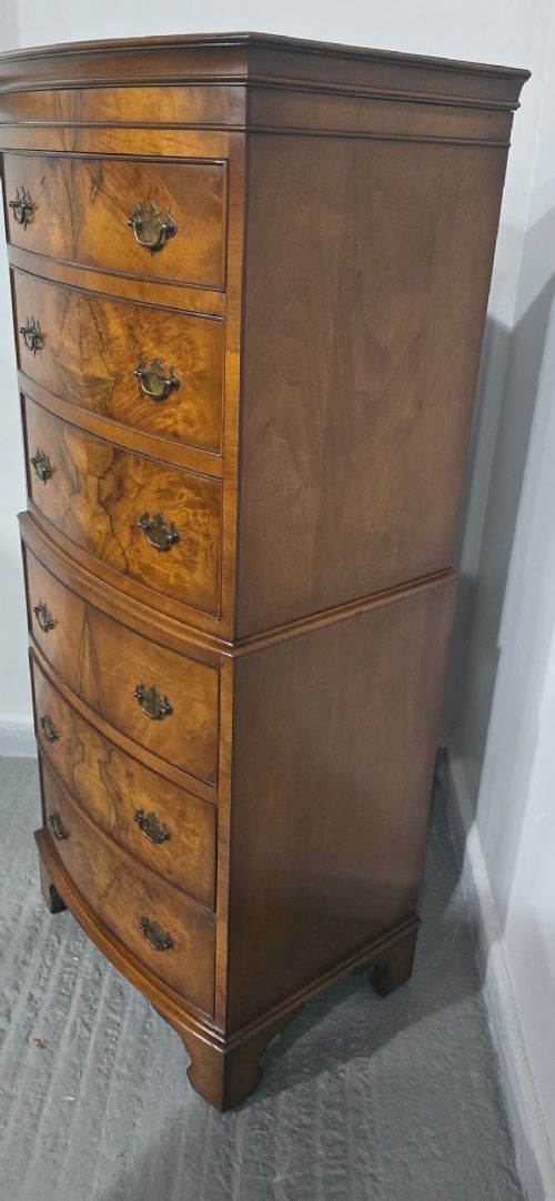 A small bowfront burr walnut chest on chest featuring stacked drawers with brass handles and bracket feet. View IV