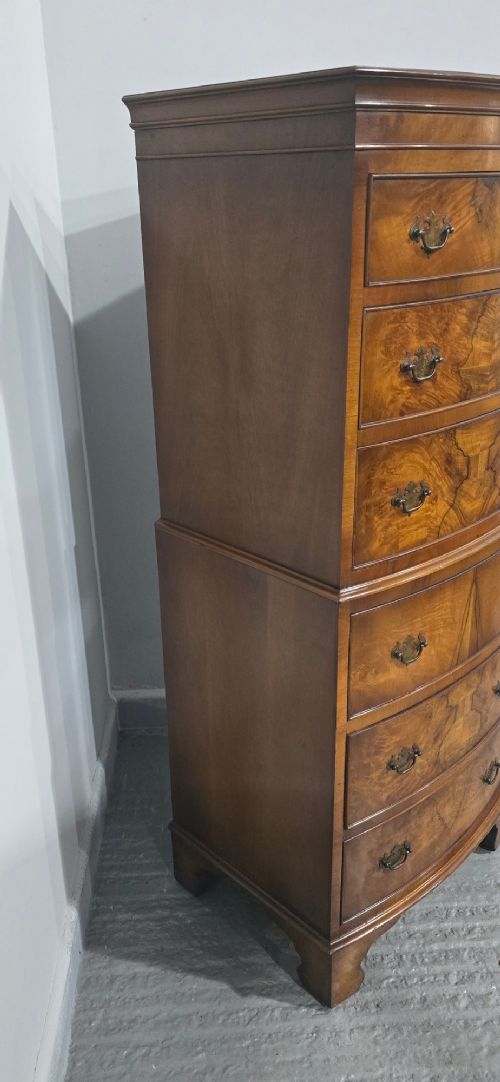 A small bowfront burr walnut chest on chest featuring stacked drawers with brass handles and bracket feet. View V