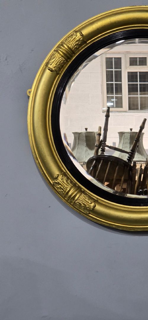 fig 1. A circular Regency style giltwood mirror featuring a black inner reeded slip and classical acanthus leaf decorative accents on the moulded frame.