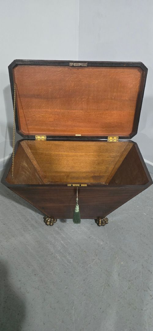 A tapered sarcophagus-shaped dark mahogany wine cooler featuring satinwood line inlay, brass lion paw feet, and a central keyhole with a green tassel. View VI