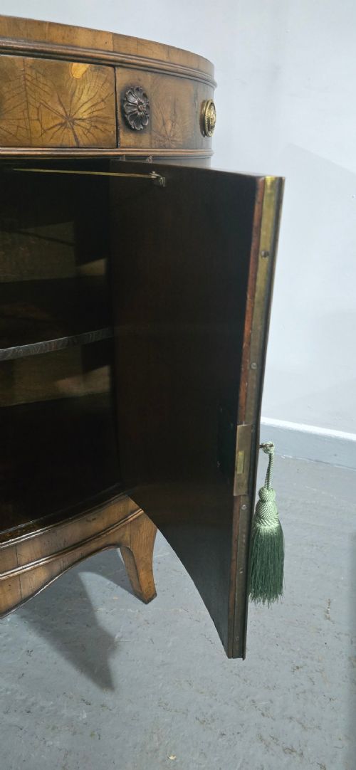 A semi-circular burr yew wood side cabinet featuring brass mounts along the frieze and central double doors. View XIII