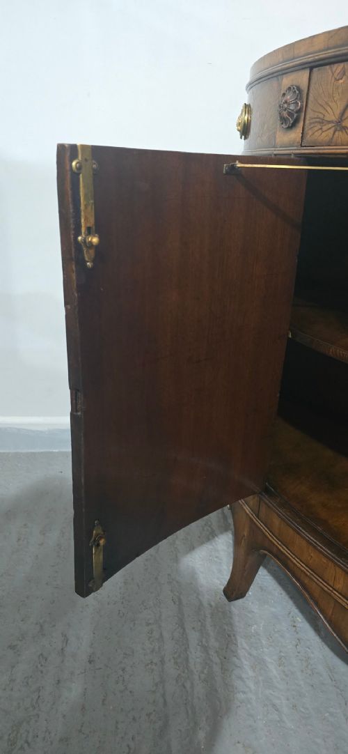A semi-circular burr yew wood side cabinet featuring brass mounts along the frieze and central double doors. View XV