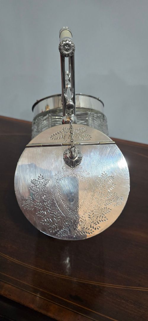 An Edwardian cut glass biscuit barrel featuring a hobnail geometric pattern, silver-plated frame, overhead handle, and pedestal base. View VI