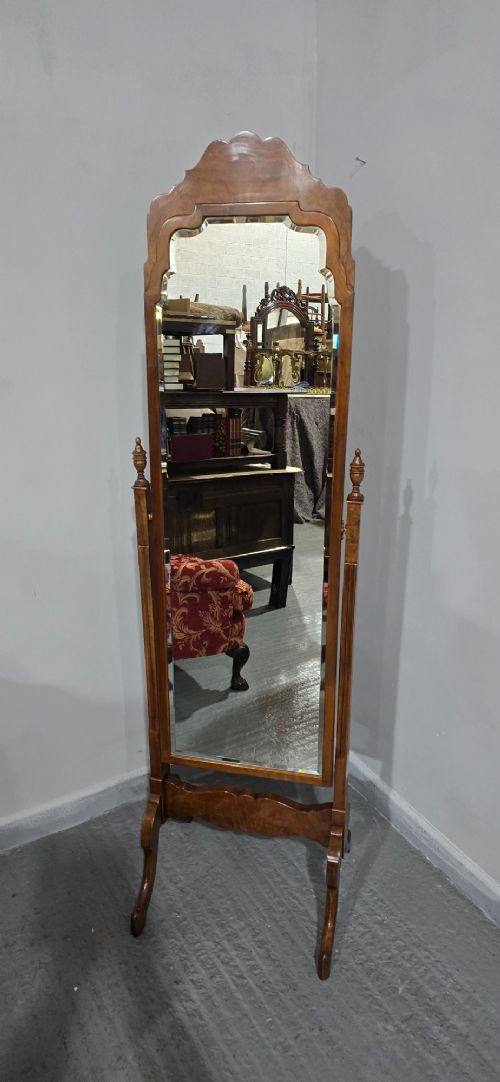 fig 1. A standing Queen Anne style burr walnut cheval mirror featuring a shaped crest, tilting glass plate, finial-topped uprights, and cabriole legs.