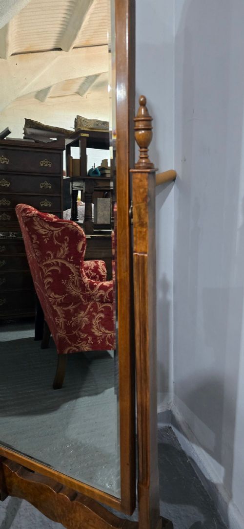 A standing Queen Anne style burr walnut cheval mirror featuring a shaped crest, tilting glass plate, finial-topped uprights, and cabriole legs. View IV