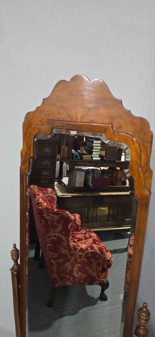 A standing Queen Anne style burr walnut cheval mirror featuring a shaped crest, tilting glass plate, finial-topped uprights, and cabriole legs. View V