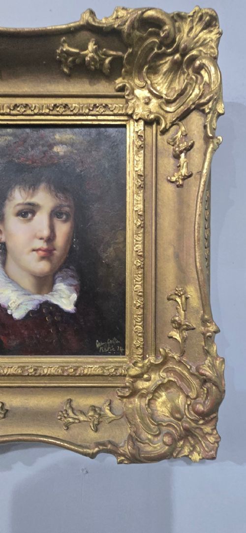 An oil painting on board depicting a young woman with dark hair and a ruffled white collar, displayed within a heavily carved gold Rococo style frame. View IV