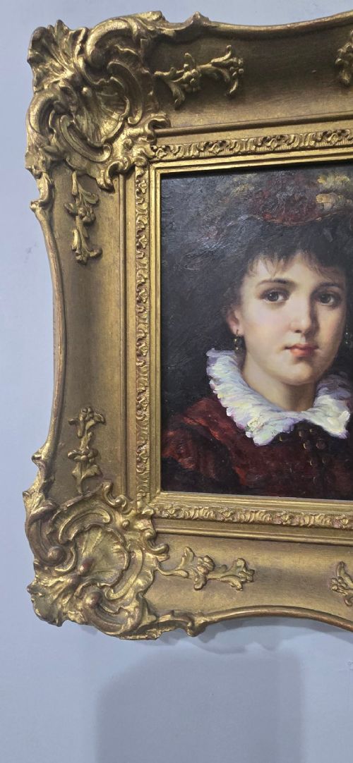 An oil painting on board depicting a young woman with dark hair and a ruffled white collar, displayed within a heavily carved gold Rococo style frame. View V