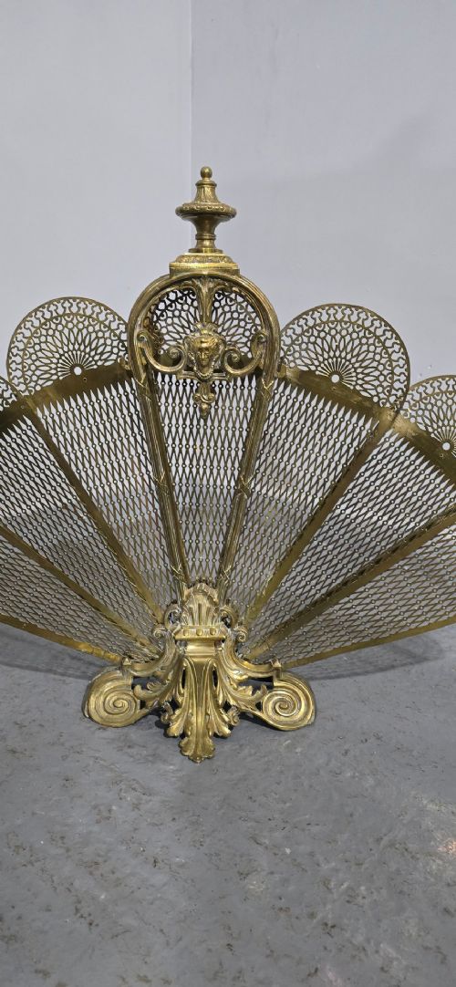 An ornate Victorian brass peacock fire screen featuring pierced filigree fan panels, a finial crest, and a cast scrollwork base. View III