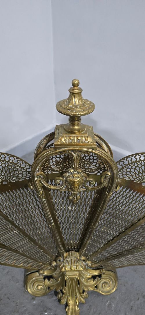 An ornate Victorian brass peacock fire screen featuring pierced filigree fan panels, a finial crest, and a cast scrollwork base. View VII