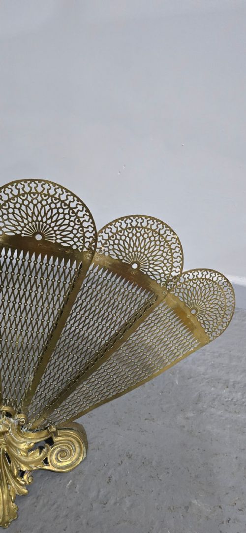 An ornate Victorian brass peacock fire screen featuring pierced filigree fan panels, a finial crest, and a cast scrollwork base. View VIII