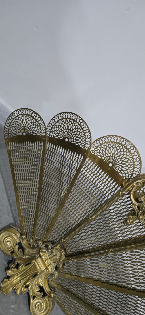 An ornate Victorian brass peacock fire screen featuring pierced filigree fan panels, a finial crest, and a cast scrollwork base. View IX
