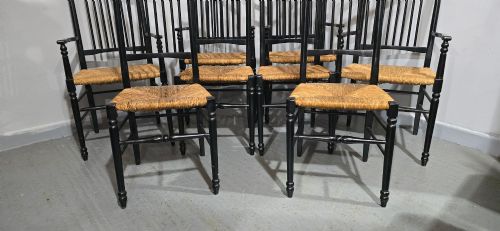 fig 1. A set of eight Arts and Crafts ebonised wooden dining chairs featuring high spindle backs and hand-woven natural rush seats.