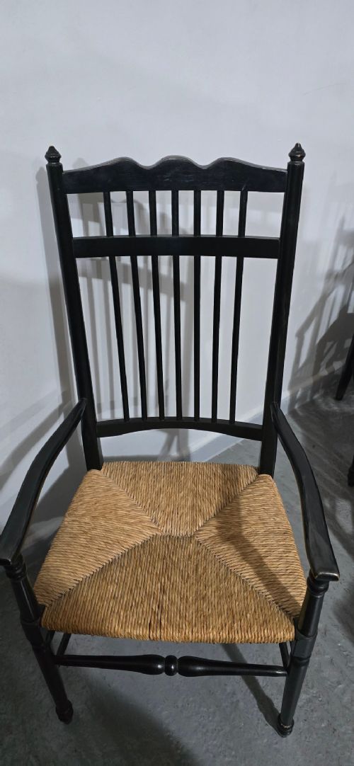 A set of eight Arts and Crafts ebonised wooden dining chairs featuring high spindle backs and hand-woven natural rush seats. View VI