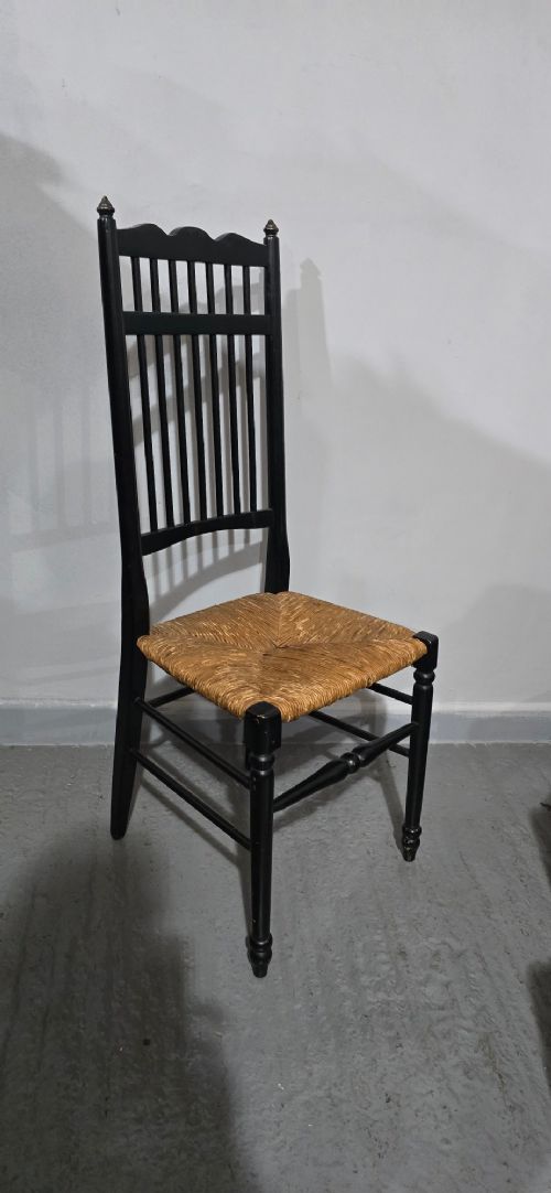 A set of eight Arts and Crafts ebonised wooden dining chairs featuring high spindle backs and hand-woven natural rush seats. View VII