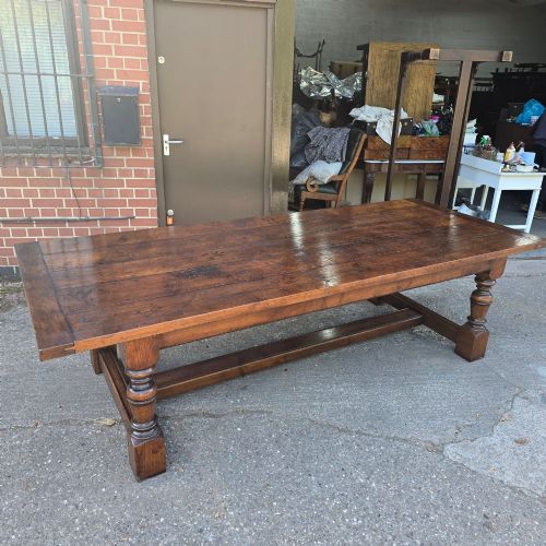 fig 1. A large solid oak refectory dining table featuring a wide plank top, breadboard ends, turned baluster legs, and a low H-stretcher base.