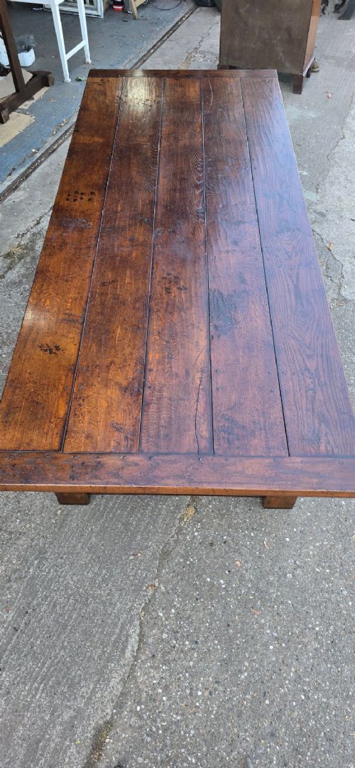 A large solid oak refectory dining table featuring a wide plank top, breadboard ends, turned baluster legs, and a low H-stretcher base. View V