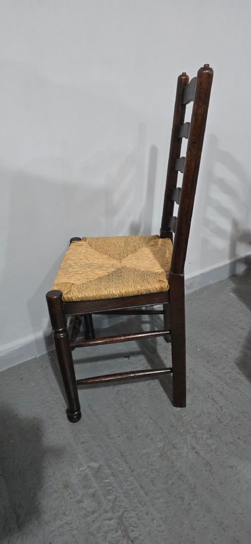 A set of eight dark oak ladder back dining chairs featuring woven rush seats, curved back rungs, and turned front legs with stretchers. View XI
