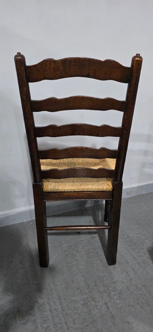 A set of eight dark oak ladder back dining chairs featuring woven rush seats, curved back rungs, and turned front legs with stretchers. View XII