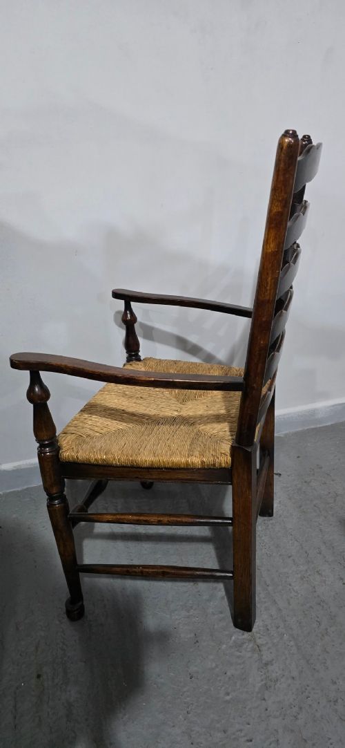 A set of eight dark oak ladder back dining chairs featuring woven rush seats, curved back rungs, and turned front legs with stretchers. View XIII