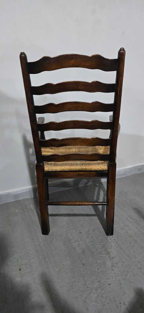 A set of eight dark oak ladder back dining chairs featuring woven rush seats, curved back rungs, and turned front legs with stretchers. View XIV