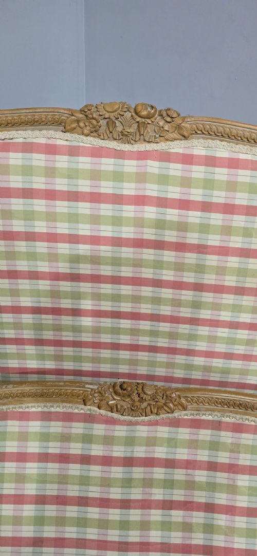 A French double bed frame with a limed wood structure, featuring floral crest carvings, fluted details, and check pattern upholstery. View V