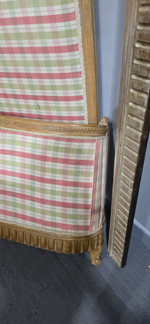 A French double bed frame with a limed wood structure, featuring floral crest carvings, fluted details, and check pattern upholstery. View VI