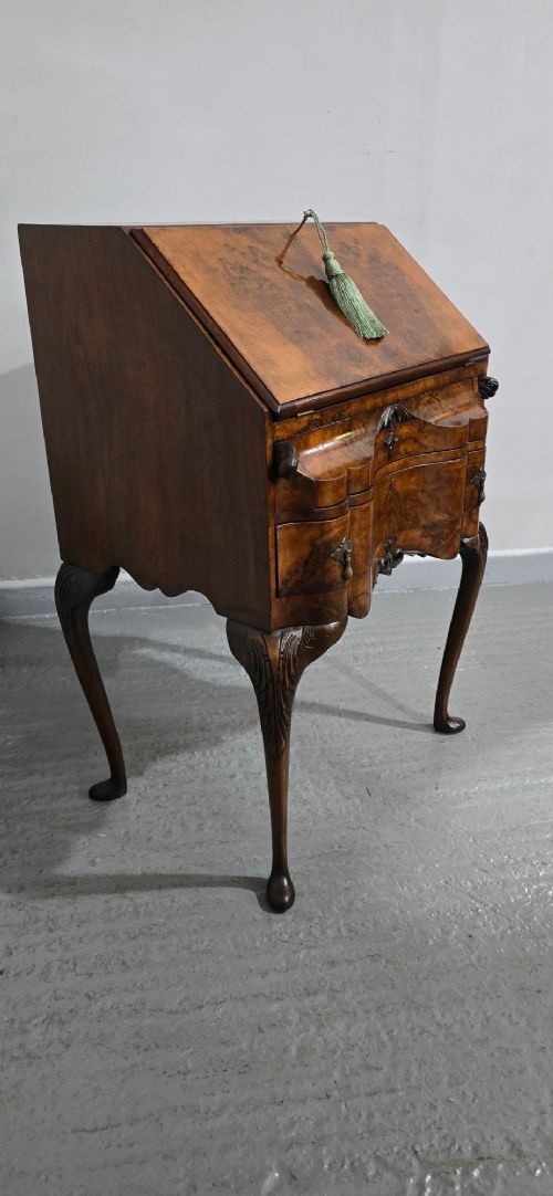 A Queen Anne style burr walnut writing bureau featuring a sloped front lid, shaped drawers with brass drop handles, and tall cabriole legs. View XII