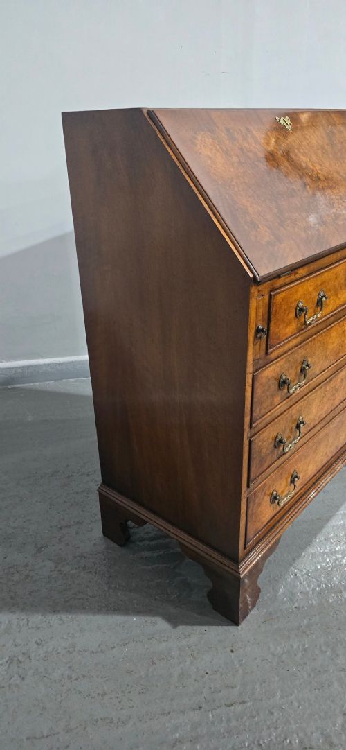 An antique Queen Anne burr walnut writing bureau featuring a sloping fall-front lid over four graduated drawers with brass drop handles and bracket feet. View IX