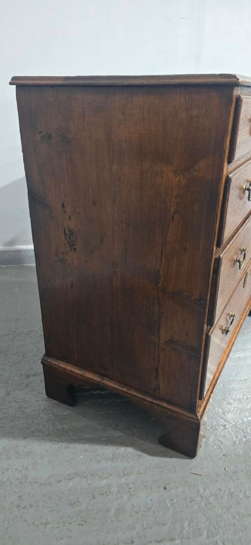 A Georgian oak chest of drawers featuring two short drawers above three long graduated drawers with brass swan-neck handles and bracket feet. View V