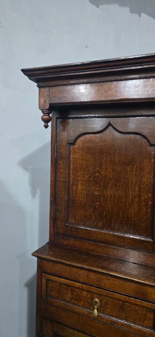 A dark oak Georgian court cupboard featuring an upper cabinet with arched panel doors, two central drawers, and a lower double-door cupboard on bracket feet. View VIII